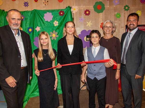 Schülerinnen und Schüler durchschneiden rotes Band bei Eröffnung in Österreich